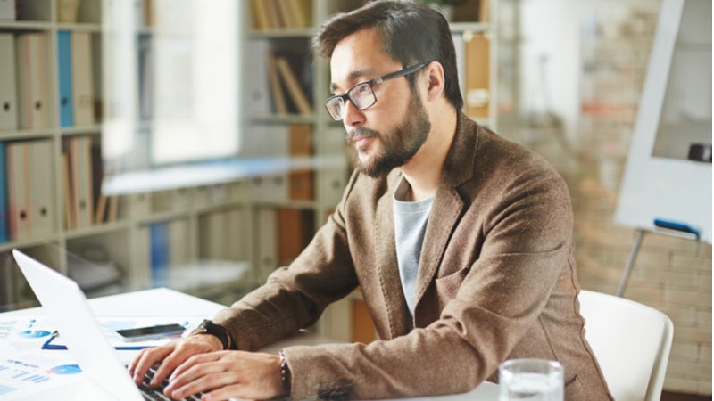 Somber businessman working on laptop