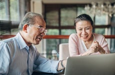 Asian couple is sitting in front of a laptop and looking at various financial options when converting their term life insurance.