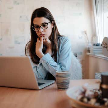 Worried girl looking at laptop screen at home.