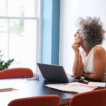 Older widow looking out of a window in an office