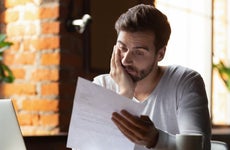Man looking stressed while reading financial documents.