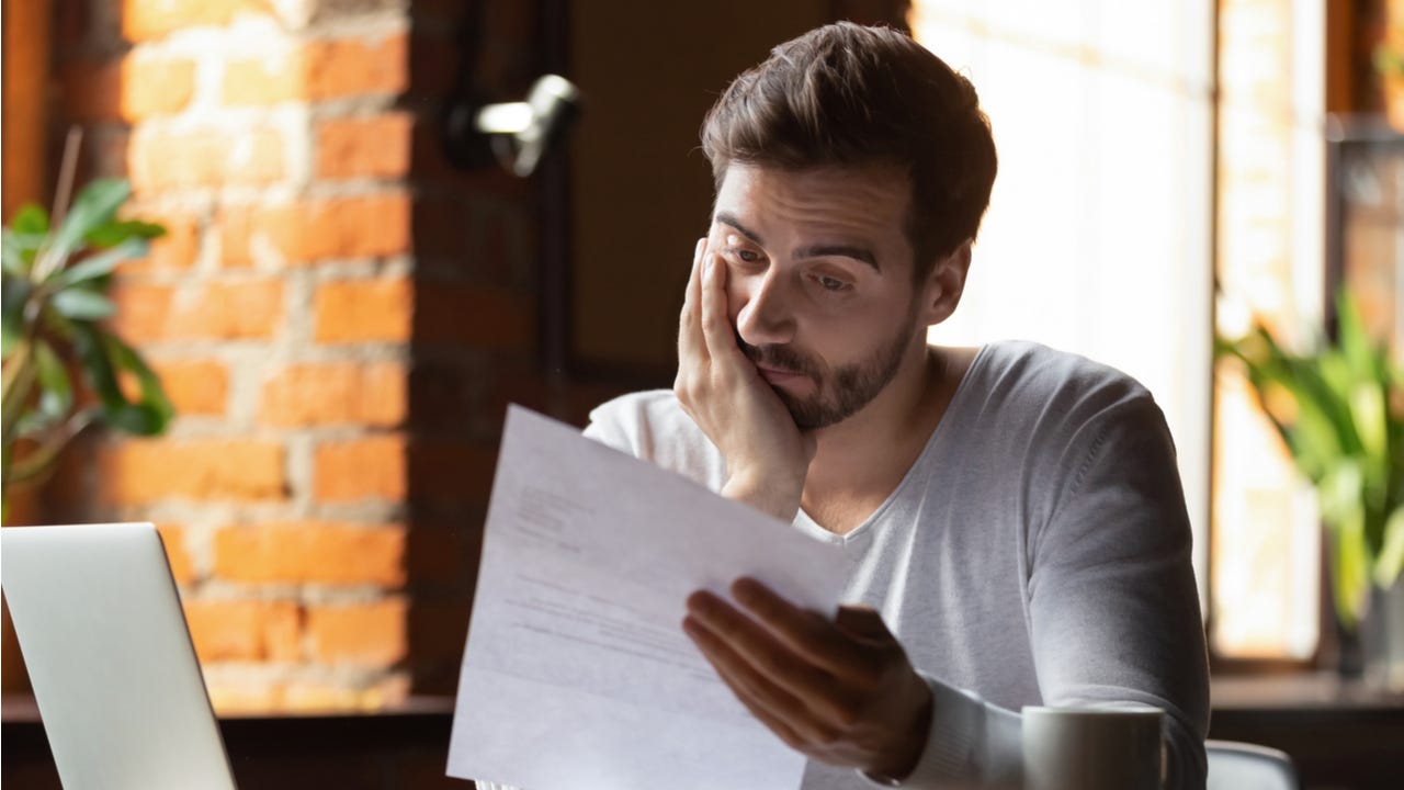 Man looking stressed while reading financial documents.