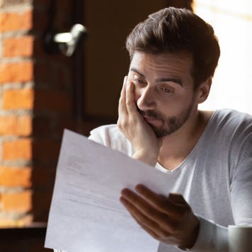 Man looking stressed while reading financial documents.