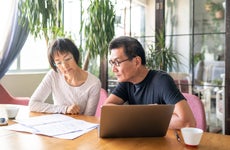 Older Asian couple sits at the kitchen table going over their finances.