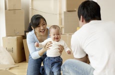 A man and woman play with their small child after a hard day of moving boxes into a new home.