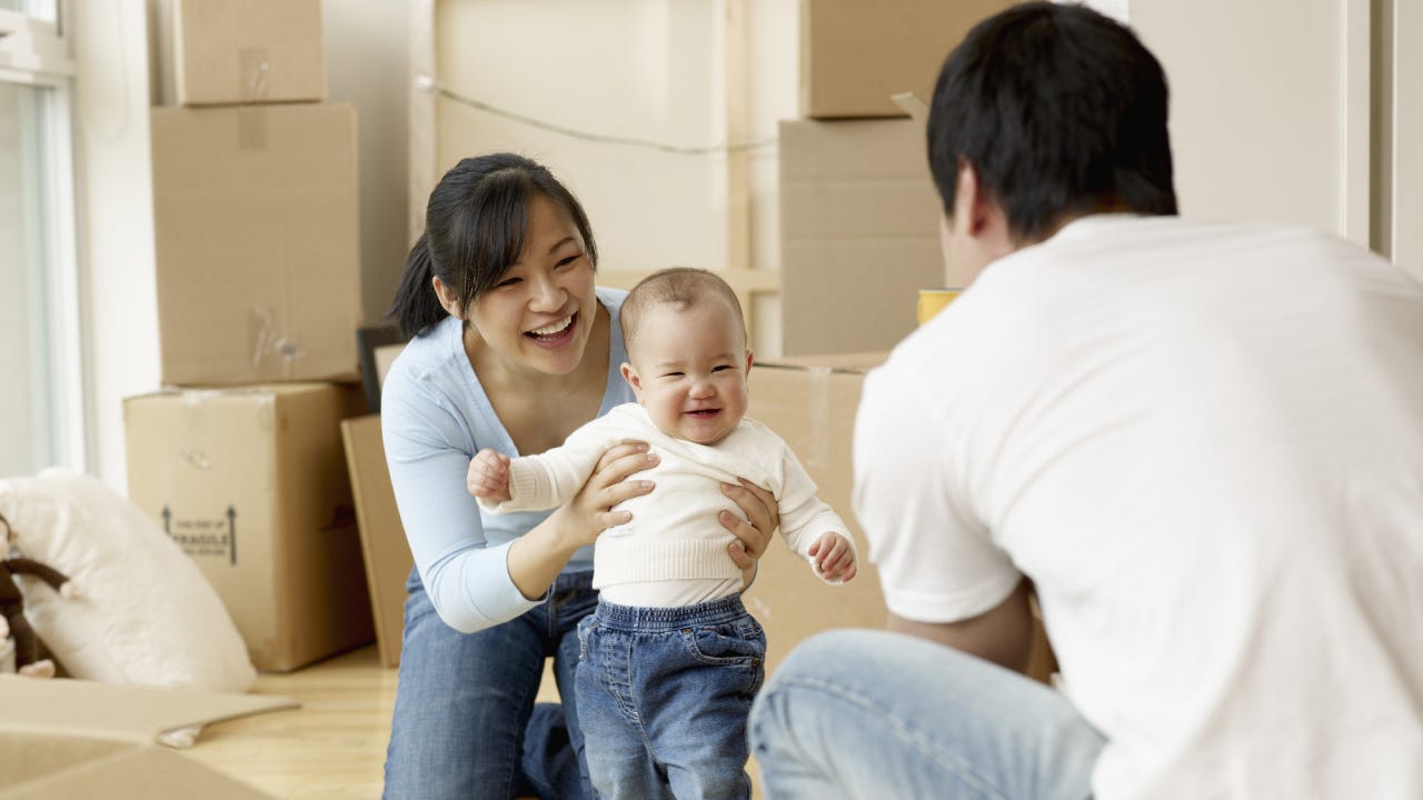A man and woman play with their small child after a hard day of moving boxes into a new home.