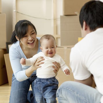 A man and woman play with their small child after a hard day of moving boxes into a new home.