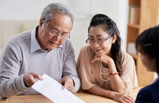 An Asian couple reviewing their options with a financial advisor after their death benefits policy has been denied.