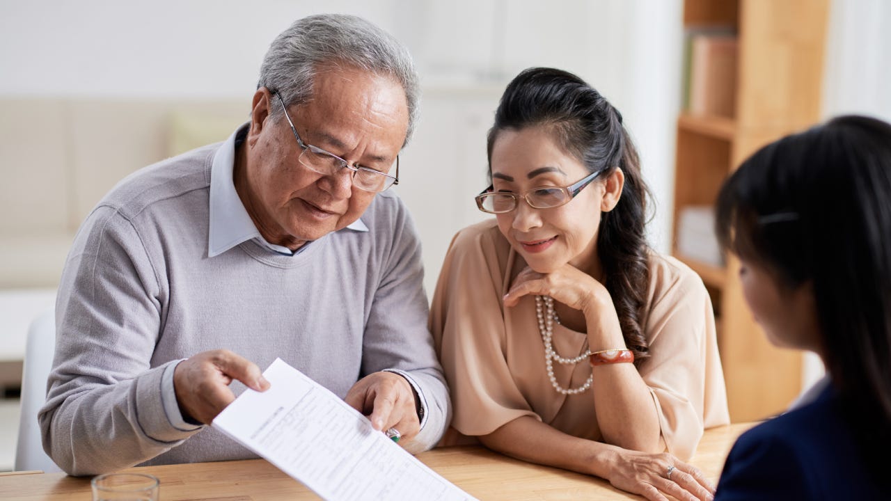 An Asian couple reviewing their options with a financial advisor after their death benefits policy has been denied.