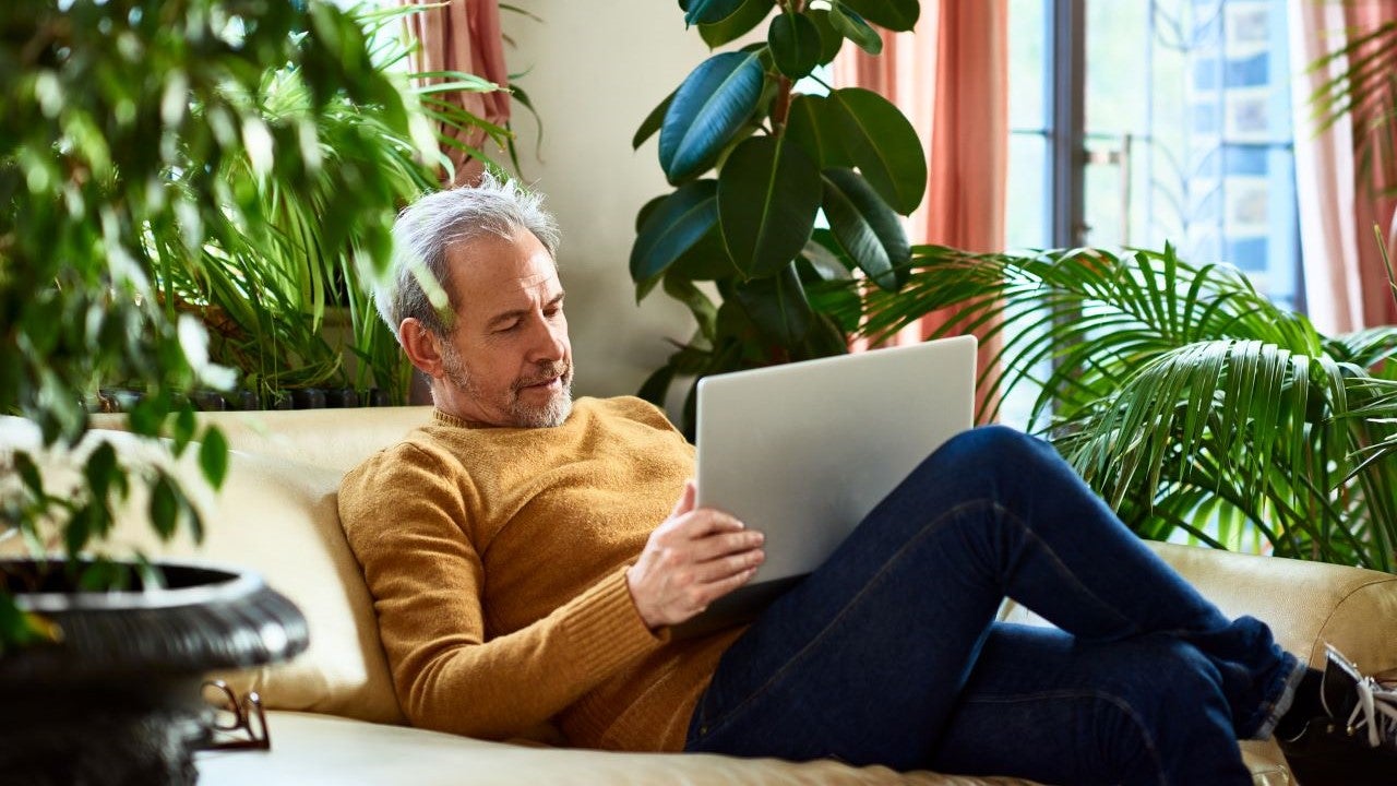 Man looking at laptop while sitting on couch