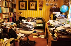 A work area or den that is full of papers and clutter.