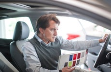 Man sitting in car looking at color samples