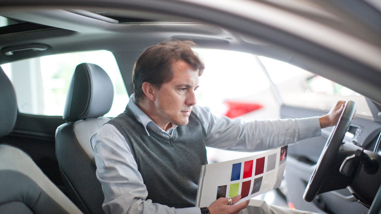 Man sitting in car looking at color samples