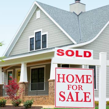 How to sell your house for cash - gray suburban home with brick front porch and "sold" sign in front yard