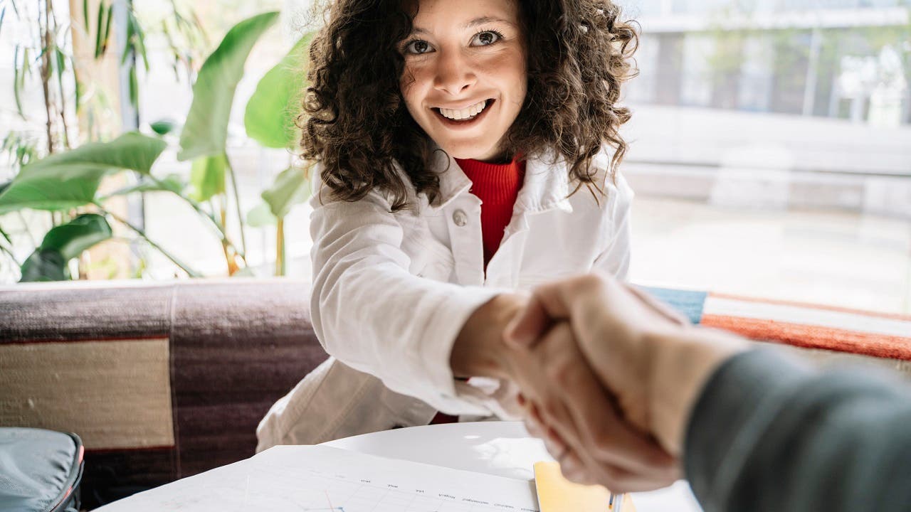 Woman shaking hands with man while sitting at table in cafe