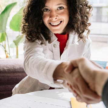 Woman shaking hands with man while sitting at table in cafe