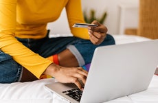 Close up woman hands using credit card to buy online on laptop - E-commerce and shopping online concept