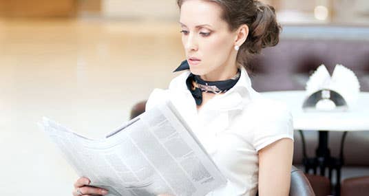 Woman wearing scarf at table reading paper © Aleksandr Markin/Shutterstock.com