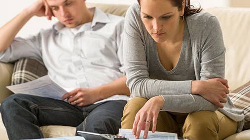 Couple working on finances on couch © CandyBox Images/Shutterstock.com