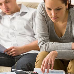 Couple working on finances on couch © CandyBox Images/Shutterstock.com
