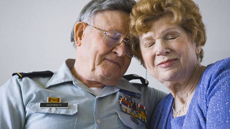 Senior military veteran resting head against wife | rubberball/Getty Images