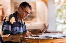 Older man doing paperwork | skynesher/Getty Images