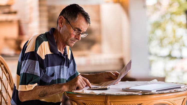 Older man doing paperwork | skynesher/Getty Images
