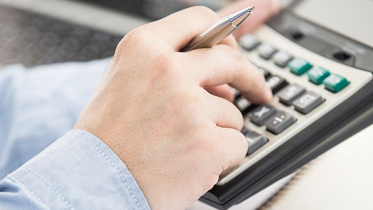 Businessman analyzing investment charts with calculator © Nonwarit/Shutterstock.com