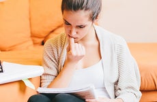 Young woman doing paperwork in living room © Peter Bernik/Shutterstock.com