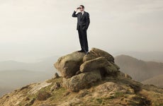 Businessman standing on a mountain looking through binoculars © Ollyy/Shutterstock.com