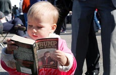 Baby looking at 'The Art of the Deal'  book| MARY SCHWALM/Getty Images