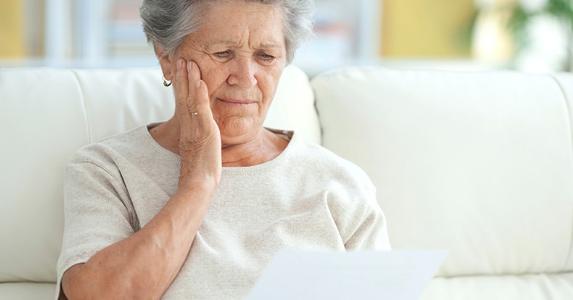Upset elderly woman reading a letter | iStock.com