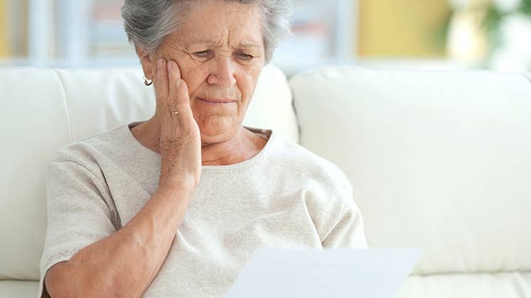 Upset elderly woman reading a letter | iStock.com