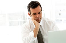 Worried businessman reading monitor screen at work © iStock