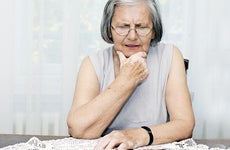 Worried senior woman sitting at desk with hand on chin © baki/Shutterstock.com