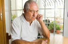 Man seated at kitchen table thinking © cunaplus/Shutterstock.com