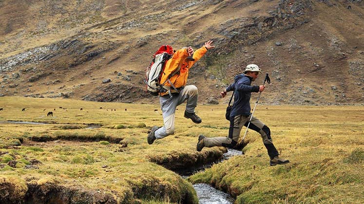 Two people jumping a small creek, outdoors © Mikadun/Shutterstock.com
