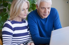 Senior couple sitting at a table looking at a laptop © Image Point Fr/Shutterstock.com