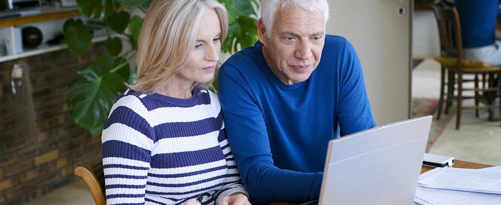 Senior couple sitting at a table looking at a laptop © Image Point Fr/Shutterstock.com