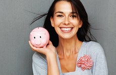Smiling young woman holding piggy bank © Yuri Arcurs - Fotolia.com