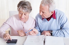 Older couple using binder and calculator © Andrey_Popov/Shutterstock.com