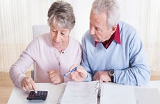 Older couple using binder and calculator © Andrey_Popov/Shutterstock.com