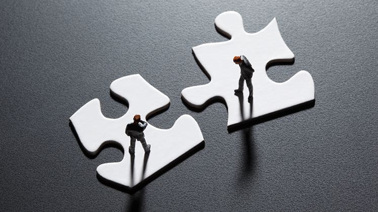 Businesesmen figurines standing on puzzle pieces © iStock
