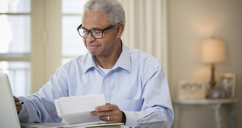 Older man happily doing paperwork | Terry Vine/Blend Images/Getty Images