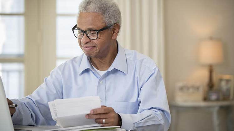 Older man happily doing paperwork | Terry Vine/Blend Images/Getty Images