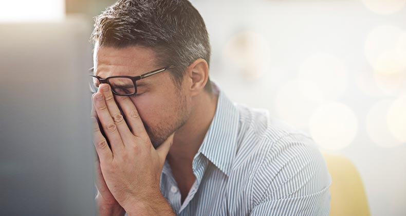 Stressed man holding bridge of nose | iStock.com