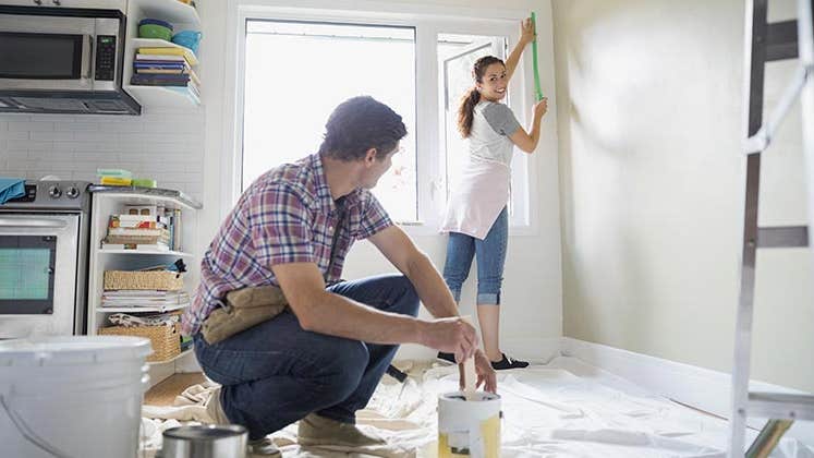 Couple painting kitchen | Hero Images/Getty Images