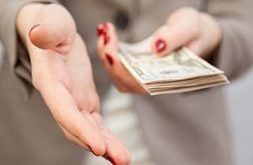Businesswoman holding out hand and money © Liudmila Pleshkun/Shutterstock.com