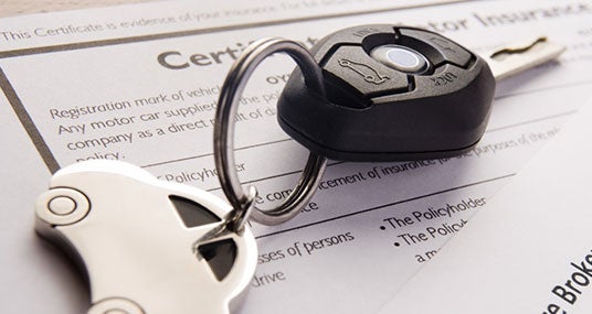 Car keys on insurance documents with toy car keychain © NAN728/Shutterstock.com
