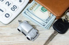 Toy car, money, keys and calculator on a table © iStock